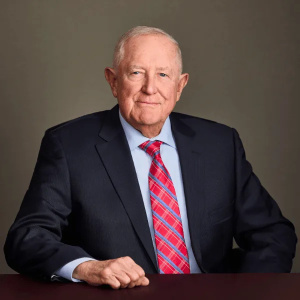 George H. Williams seated at a desk in a dark suit and red tie