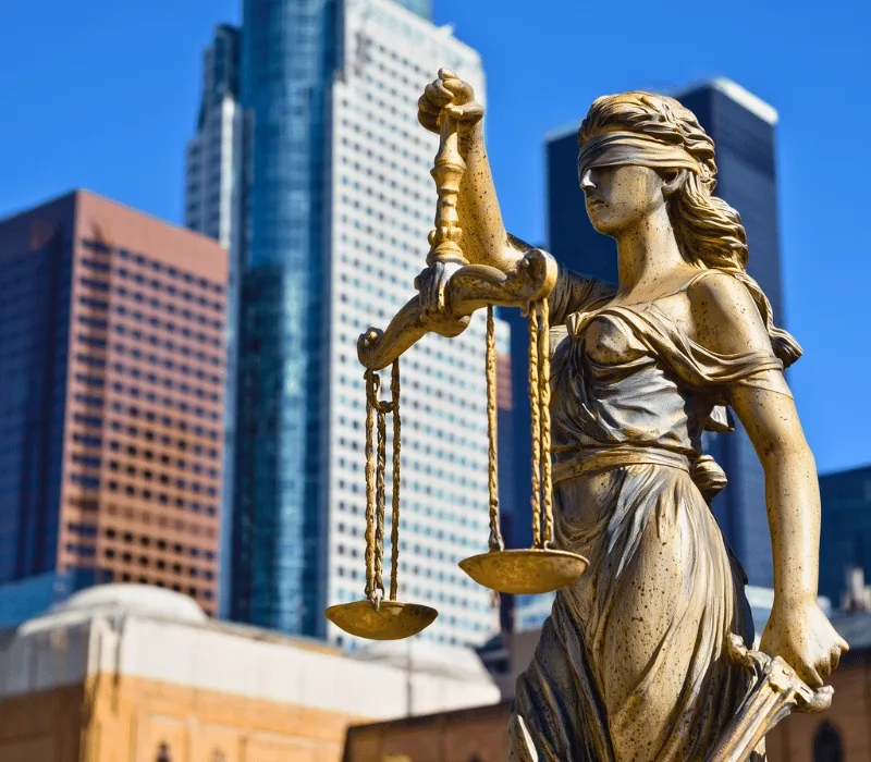 Statue of Lady Justice holding scales, with downtown Los Angeles office towers behind it
